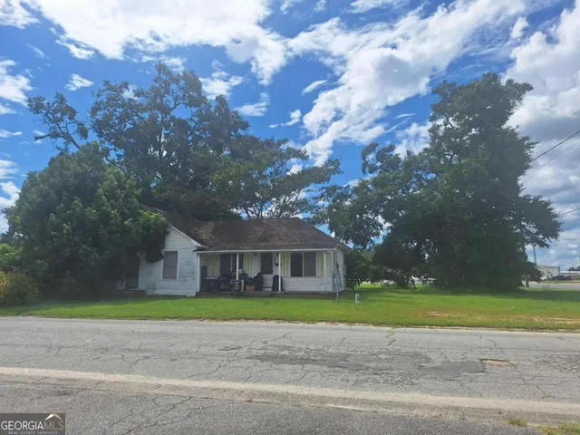 a view of a house with a big yard and large trees
