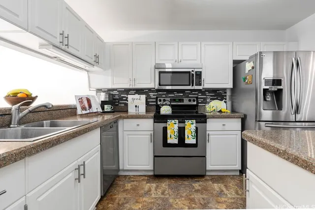 a kitchen with stainless steel appliances granite countertop a sink a stove a refrigerator a granite counter tops and white cabinets