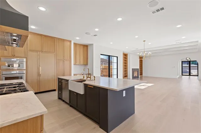 a large kitchen with stainless steel appliances a sink a stove and a refrigerator