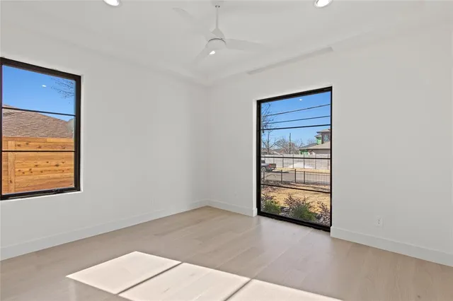 an empty room with wooden floor closet and windows