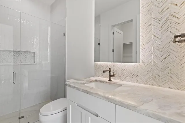 a bathroom with a granite countertop sink a toilet and shower