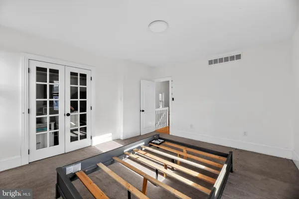 a view of an empty room with wooden floor and windows