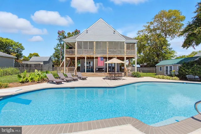 an aerial view of a house with swimming pool and large trees