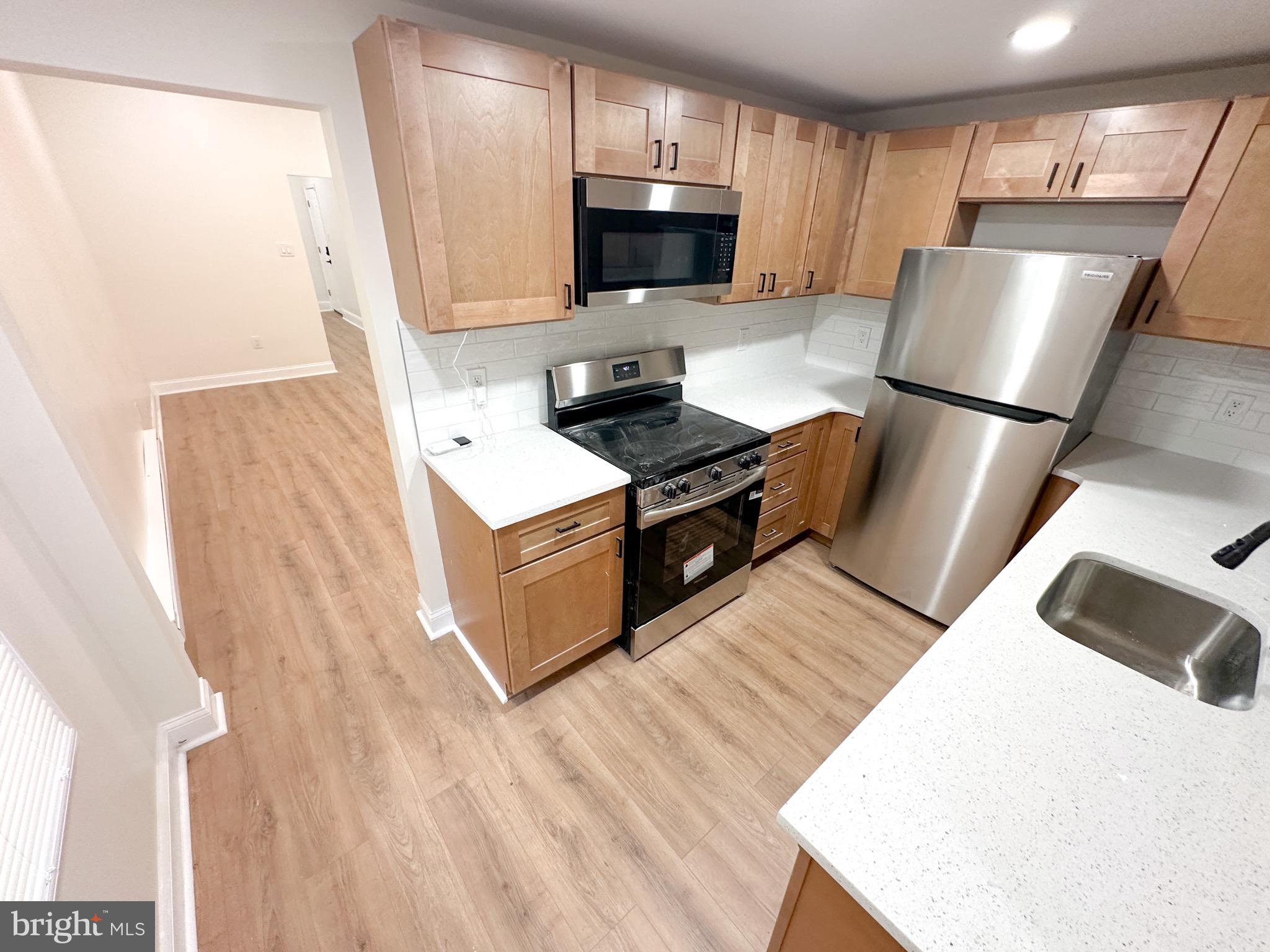 a kitchen with stainless steel appliances granite countertop a refrigerator stove top oven and sink
