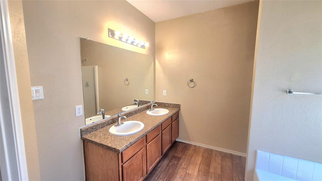 953 Hannah Way Dallas, TX 75253 - Photo 17 of 22 Bathroom featuring a double vanity with wood-finish cabinetry and a speckled countertop