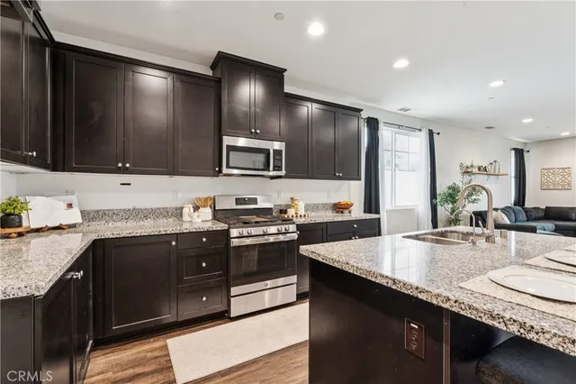 a kitchen with stainless steel appliances granite countertop a sink stove and refrigerator