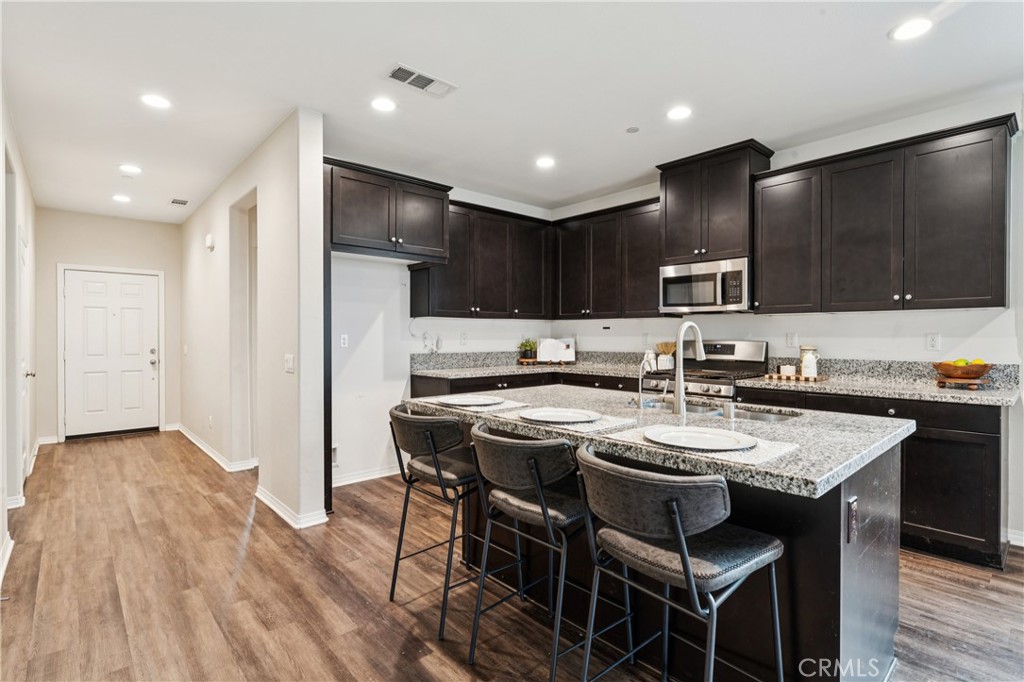 30535 Ridgely Way Menifee, CA 92584 - Photo 18 of 37 a kitchen with a dining table chairs refrigerator and cabinets