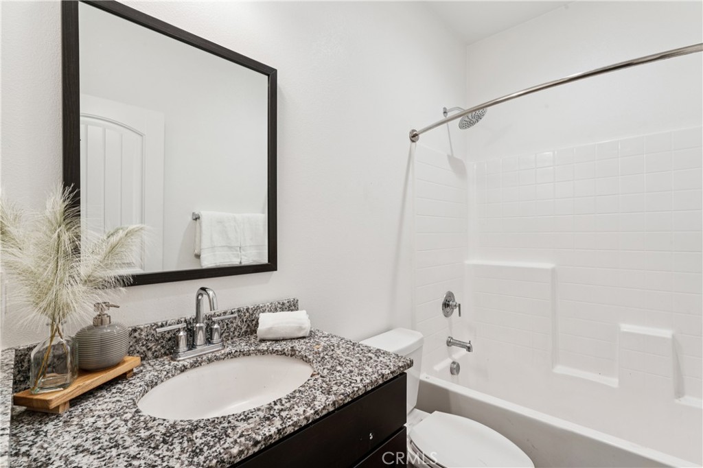 30535 Ridgely Way Menifee, CA 92584 - Photo 10 of 37 a bathroom with a granite countertop sink toilet a mirror and shower