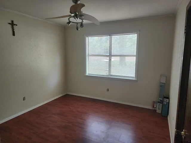 an empty room with wooden floor fan and windows