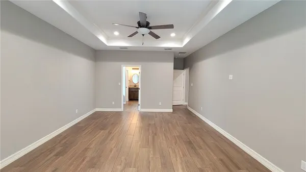 an empty room with wooden floor and ceiling fan