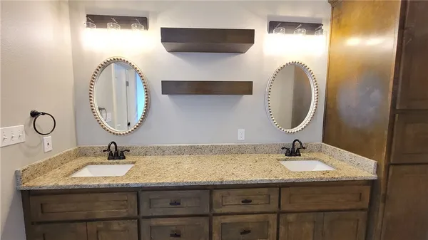 a bathroom with a granite countertop double vanity sink and a mirror