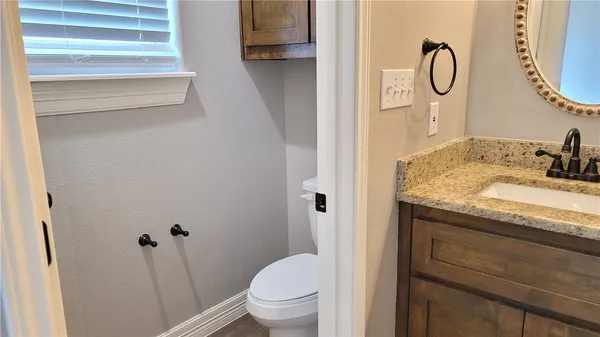 a bathroom with a granite countertop sink toilet and a mirror