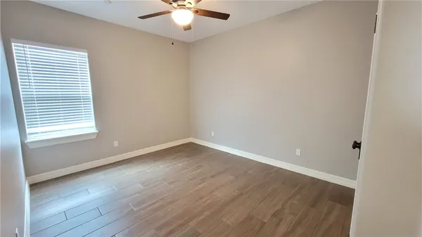 a view of a room with wooden floor and a ceiling fan