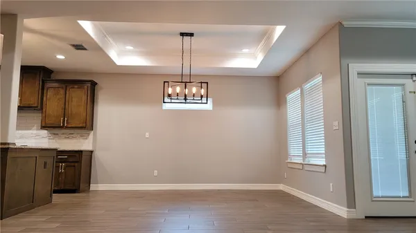 a view of an empty room with window and wooden floor