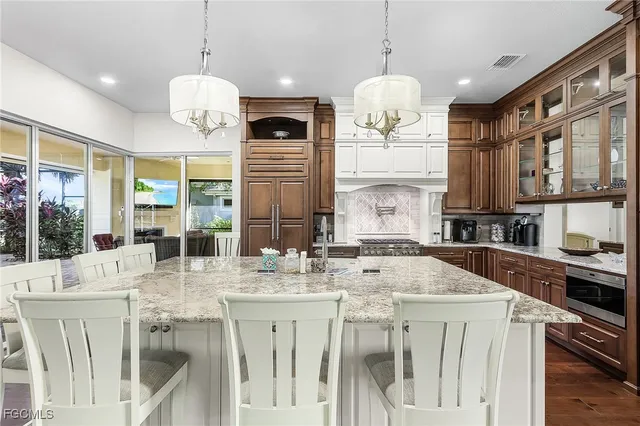 a kitchen with stainless steel appliances kitchen island granite countertop a stove a sink dishwasher and white cabinets with wooden floor