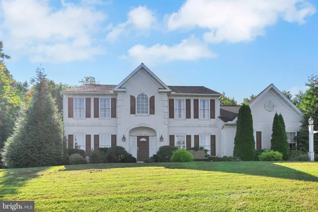 a view of house with a big yard and large trees