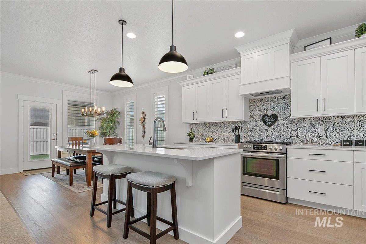1685 Shoal Point Avenue Middleton, ID 83644 - Photo 14 of 44 Kitchen featuring decorative backsplash, stainless steel electric stove, pendant lighting, white cabinets, and crown molding