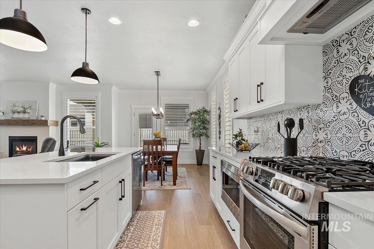 1685 Shoal Point Avenue Middleton, ID 83644 - Photo 18 of 44 Kitchen with appliances with stainless steel finishes, white cabinetry, a glass covered fireplace, range hood, and a textured ceiling