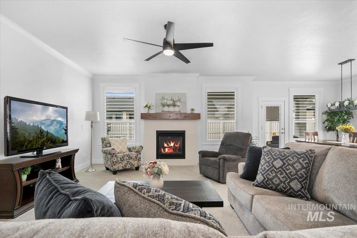 1685 Shoal Point Avenue Middleton, ID 83644 - Photo 23 of 44 Carpeted living room with a glass covered fireplace, crown molding, and a ceiling fan