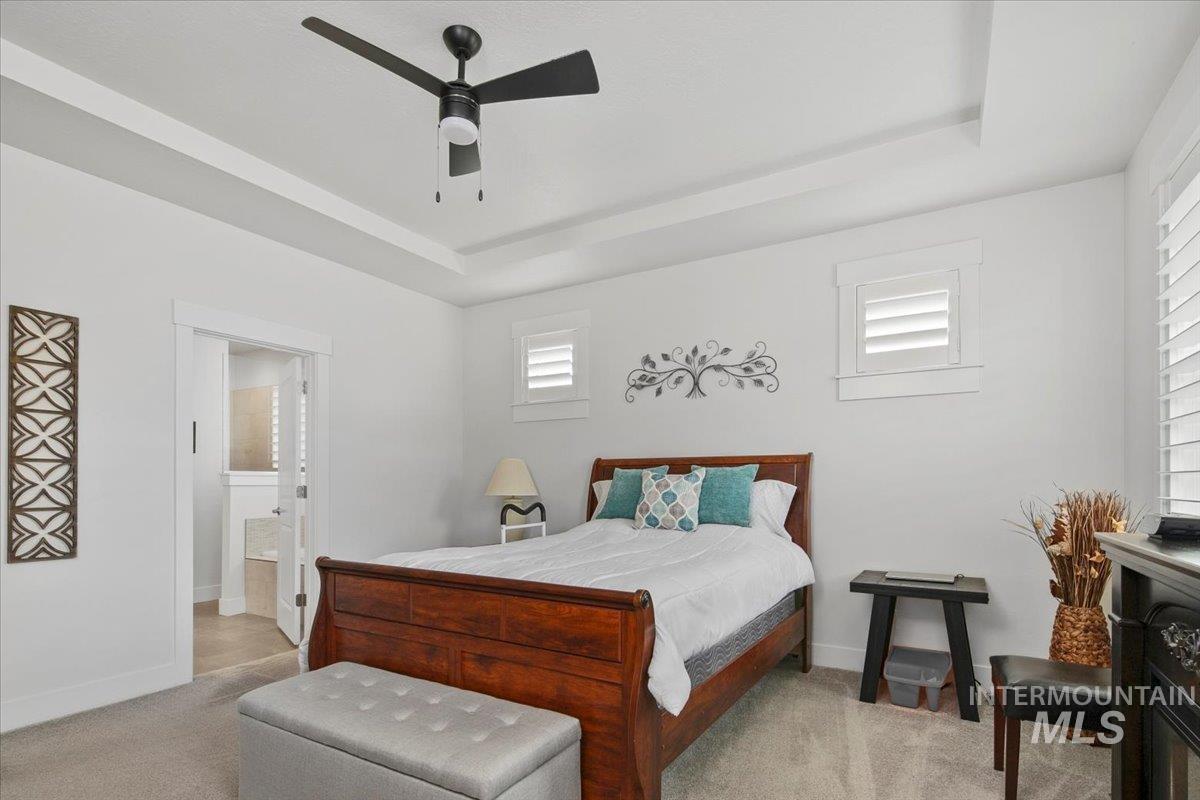 1685 Shoal Point Avenue Middleton, ID 83644 - Photo 26 of 44 Bedroom featuring a tray ceiling, light carpet, ensuite bathroom, and a ceiling fan