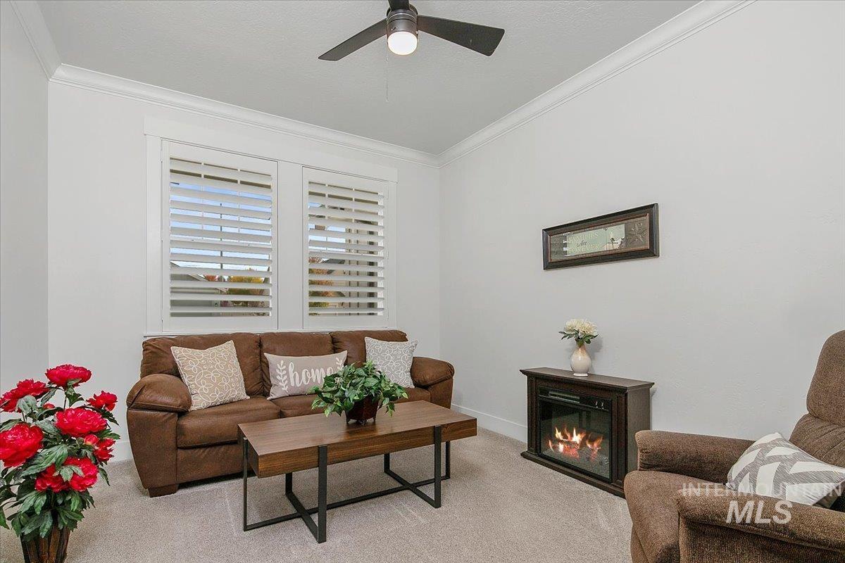 1685 Shoal Point Avenue Middleton, ID 83644 - Photo 5 of 44 Carpeted living area featuring crown molding, a glass covered fireplace, and a ceiling fan