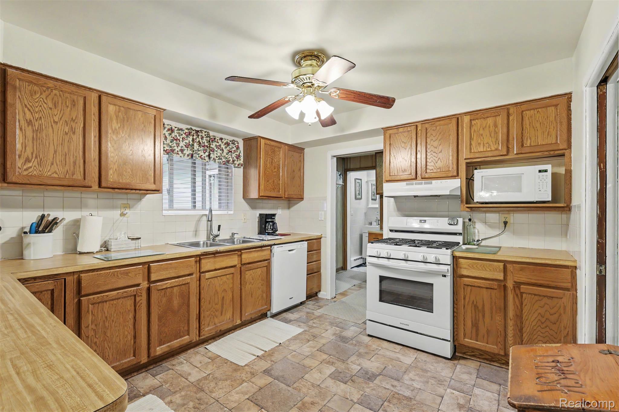 45223 Wear Road Belleville, MI 48111 - Photo 15 of 60 Kitchen featuring wood-finish cabinetry, tile flooring, white tile backsplash, a gas range, and a built-in microwave shelf