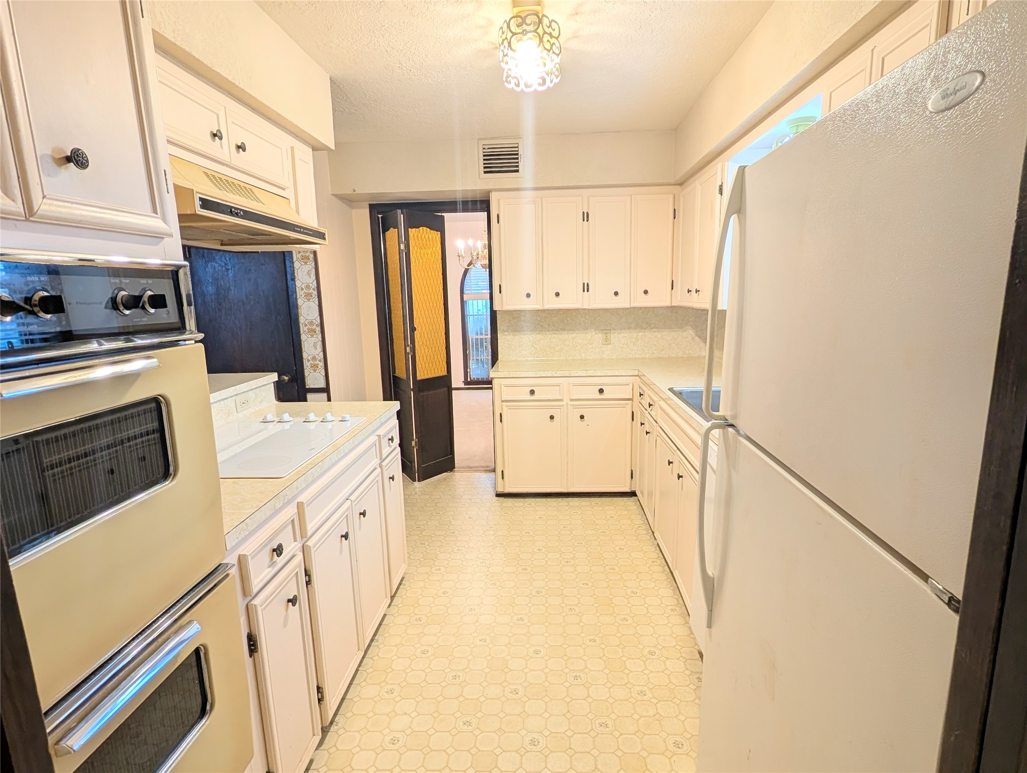 4779 Mixville Road Sealy, TX 77474 - Photo 13 of 47 Kitchen features vintage appliances, soft white cabinetry, and a compact layout with a cozy feel. It has a tile floor and a central light fixture, offering a classic and functional space.