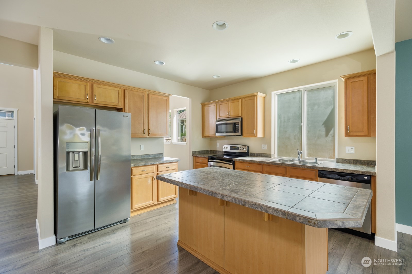 7365 Radius Loop Southeast Lacey, WA 98513 - Photo 6 of 24 a kitchen with stainless steel appliances granite countertop a refrigerator a stove and a sink with wooden floor