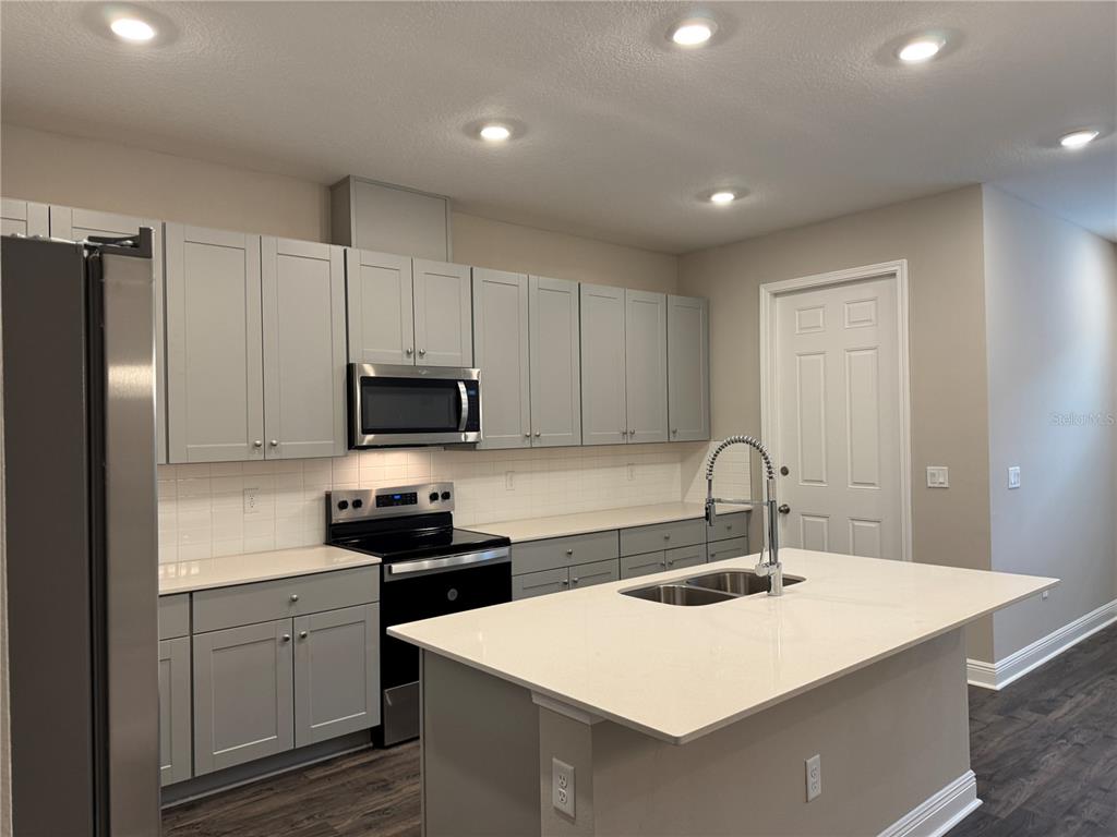 16434 Hamlin Hills Road Winter Garden, FL 34787 - Photo 10 of 50 a kitchen with a sink a stove a refrigerator and white cabinets