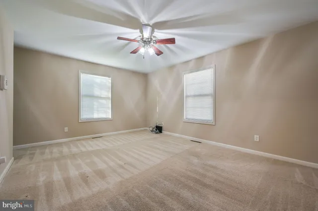 an empty room with windows and fan