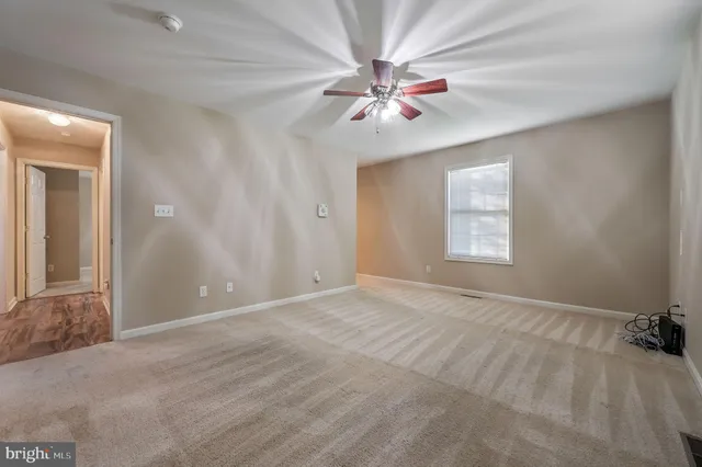 a view of an empty room with window and chandelier fan