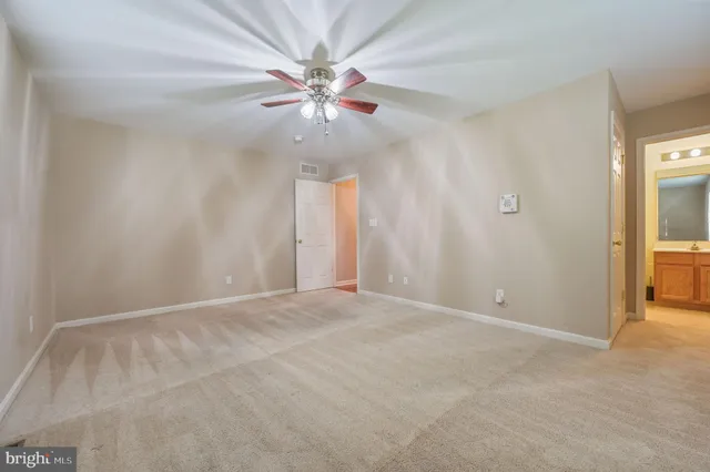 an empty room with chandelier fan and windows