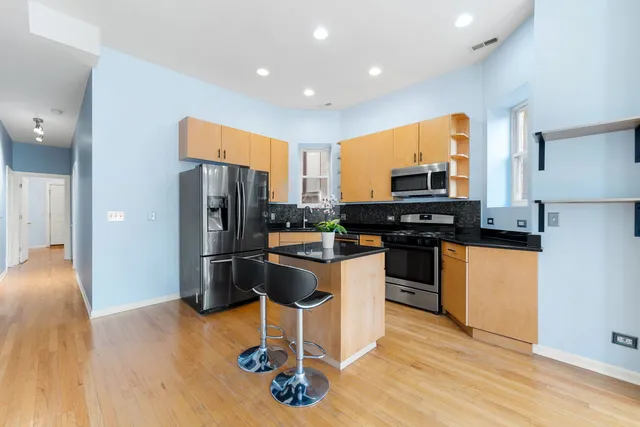 a kitchen with kitchen island granite countertop a stove top oven a sink a counter space and cabinets