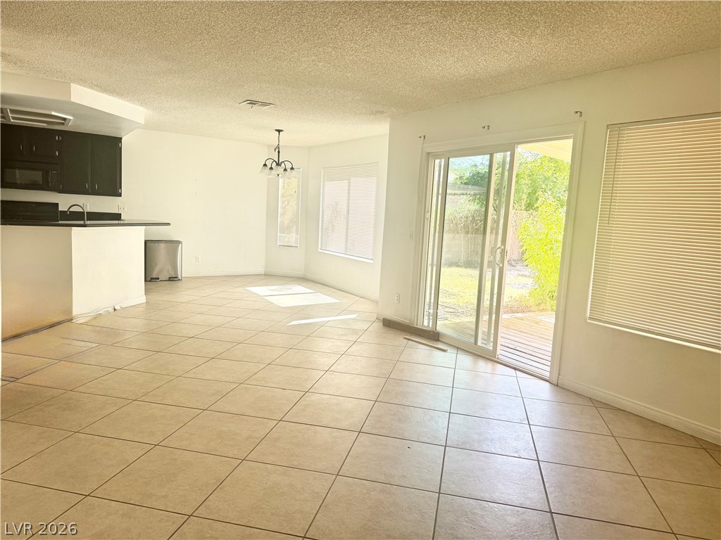135 Primero Way Henderson, NV 89074 - Photo 6 of 15 Natural light floods this versatile living area, boasting a sleek kitchen island and direct outdoor access.