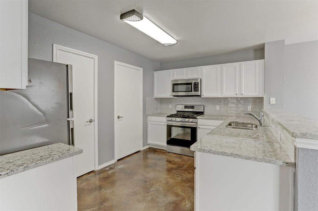 5913 Silver Screen Drive Austin, TX 78747 - Photo 6 of 31 a kitchen with granite countertop a stove a sink and a microwave