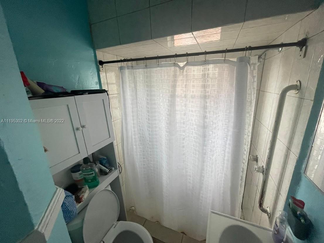 3040 Northwest 13th Avenue Miami, FL 33142 - Photo 17 of 51 a bathroom with a shower curtain and toilet
