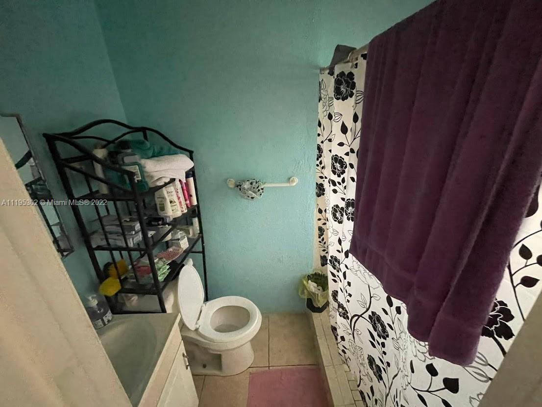 3040 Northwest 13th Avenue Miami, FL 33142 - Photo 45 of 51 a bathroom with a toilet and a shower curtain