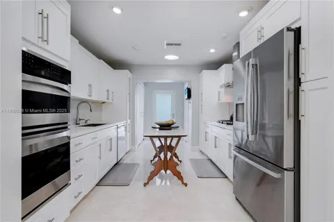 a kitchen with stainless steel appliances a table chairs and a view of living room