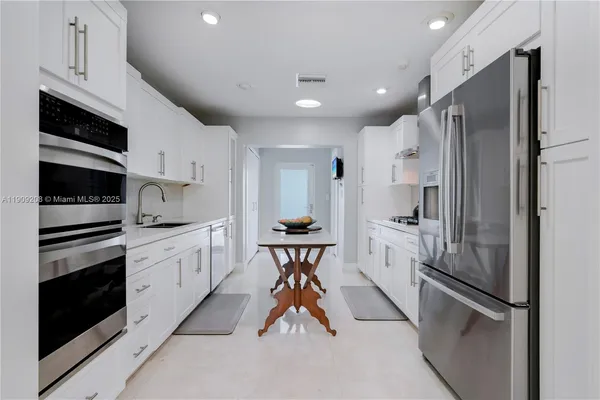 a kitchen with stainless steel appliances a table chairs and a view of living room