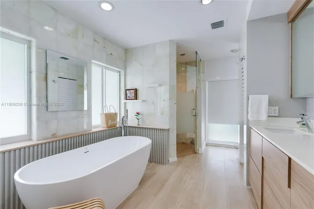 a bathroom with a tub a sink a window and a shower