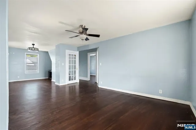 a view of an empty room with window and wooden floor