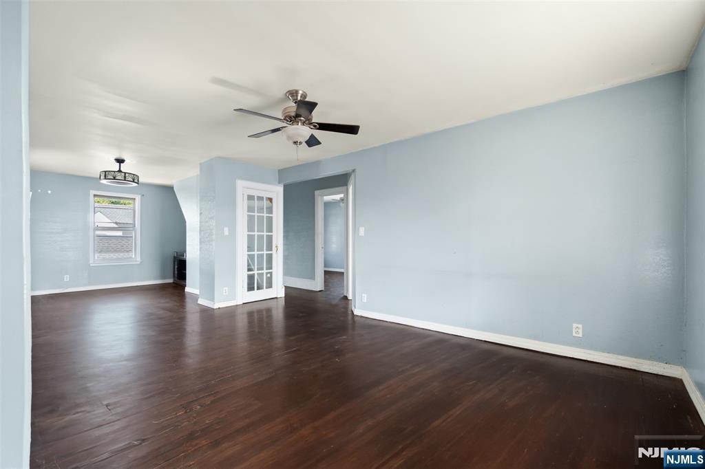 a view of an empty room with window and wooden floor