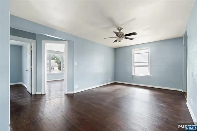 an empty room with wooden floor and ceiling fan