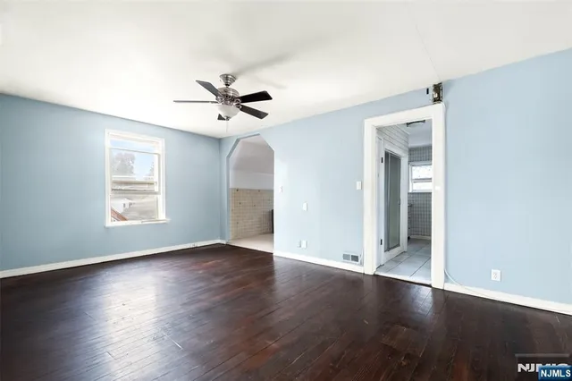 a view of an empty room with window and wooden floor