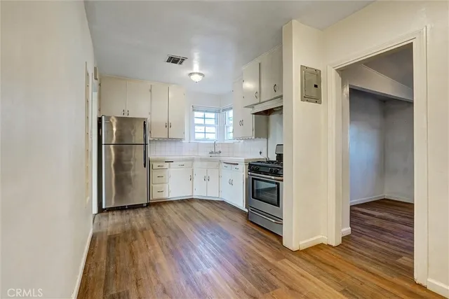 a kitchen with a refrigerator a stove top oven and wooden floor