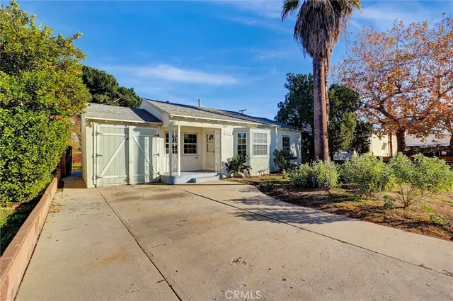 a front view of a house with a garden and trees