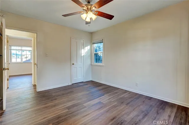 an empty room with wooden floor chandelier fan and windows