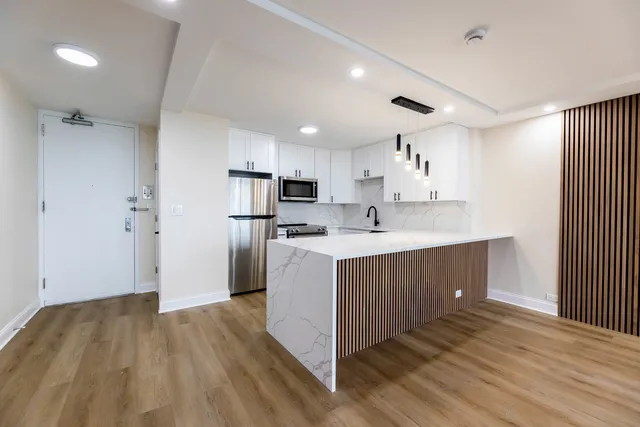 a kitchen with kitchen island a sink wooden floor and stainless steel appliances