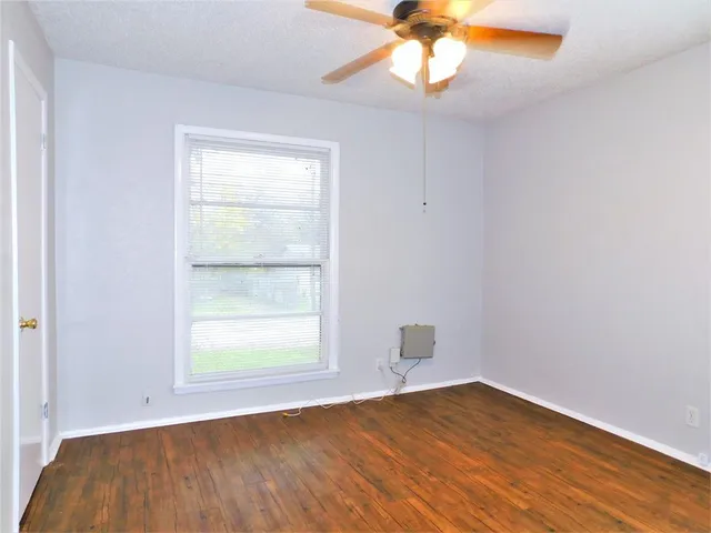 an empty room with a window and wooden floor