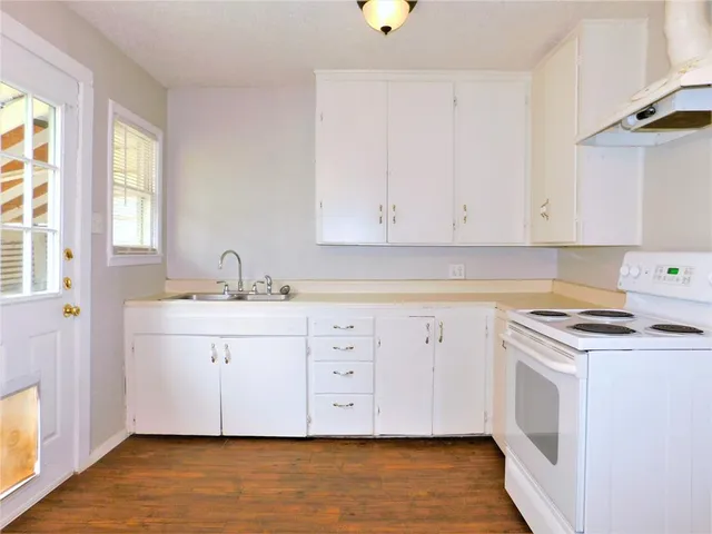 a view of cabinets a sink and a stove with wooden floor